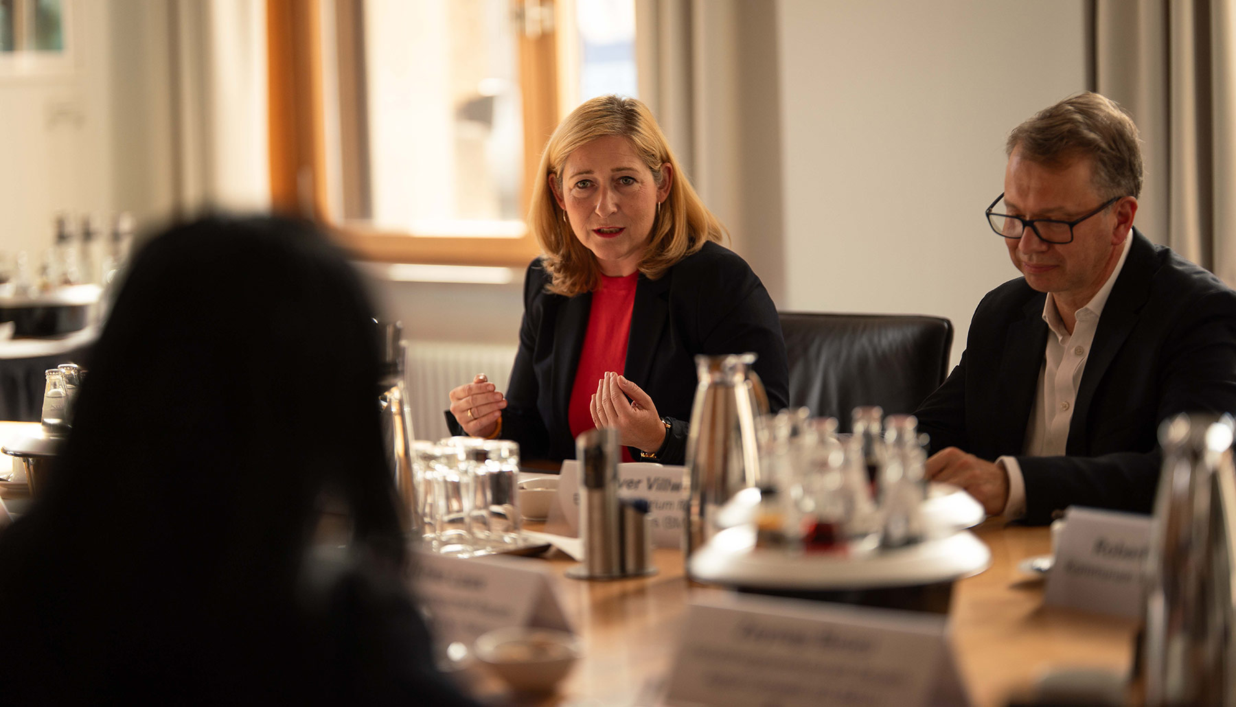 Lilian Tschan spricht zu den weiteren Teilnehmenden am Konferenztisch. Im Fokus sind Lilian Tschan und Peer-Oliver Villwock.