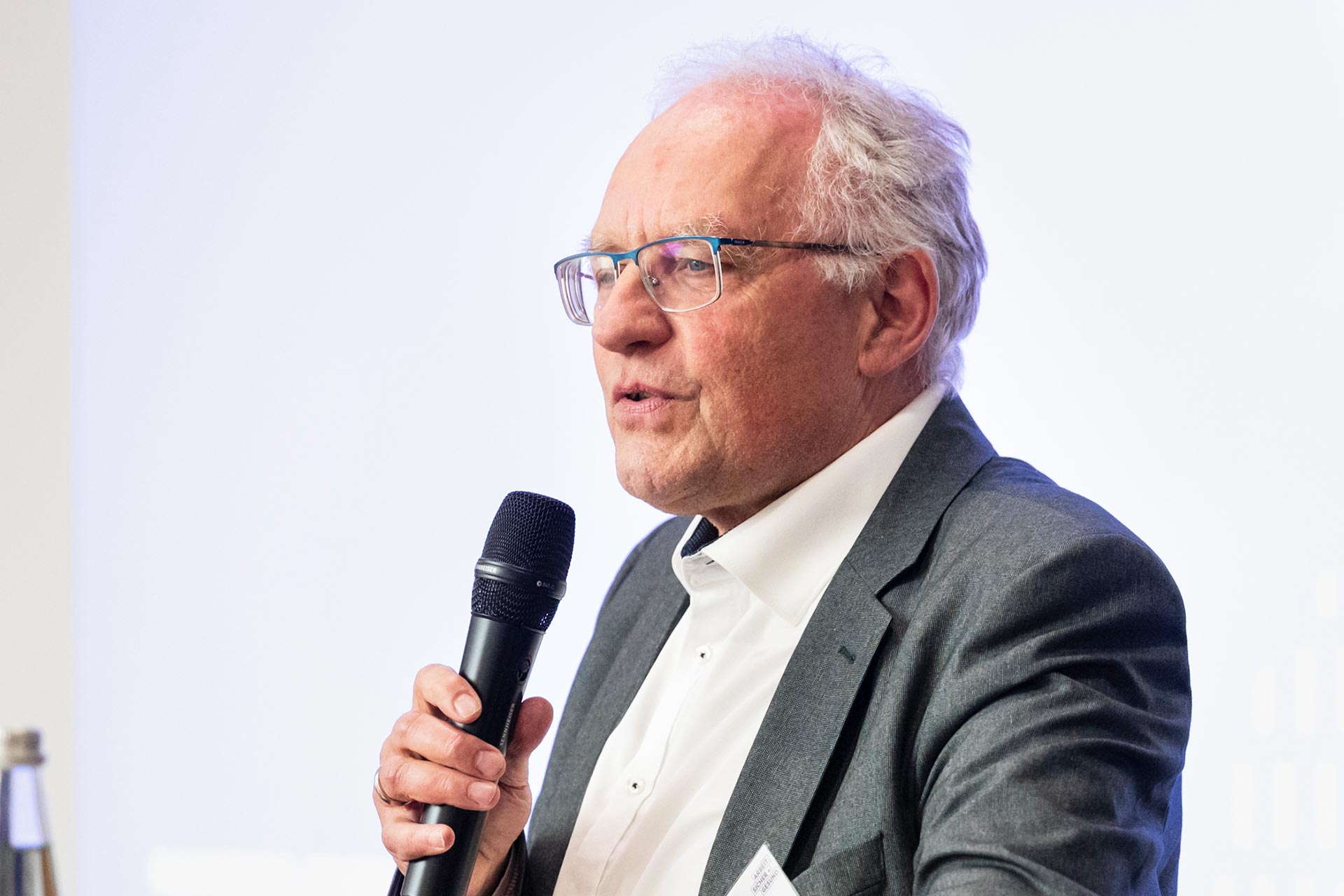 Ein Mann steht an einem Stehtisch und spricht in ein Mikrofon.
