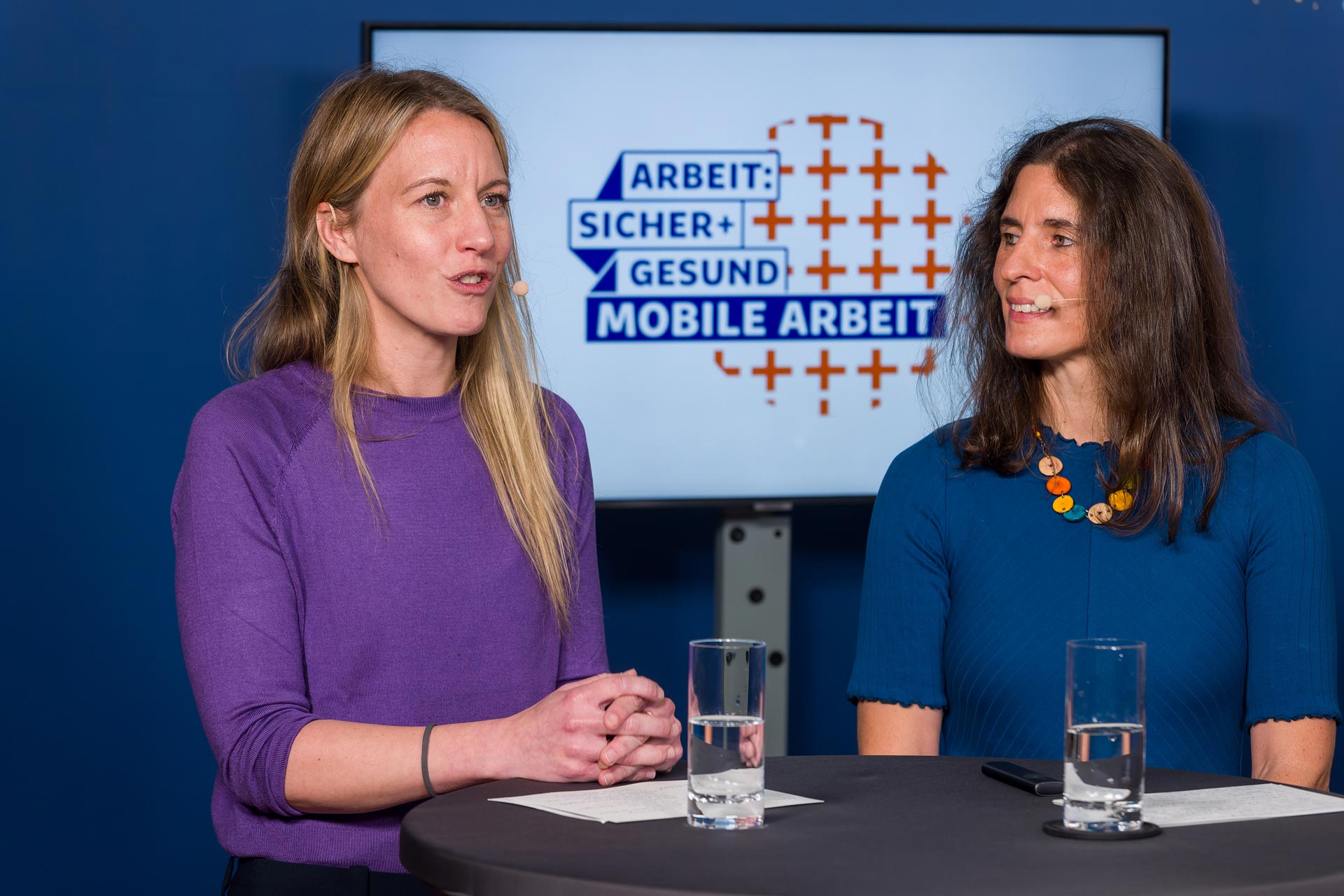 Zwei Frauen stehen sprechend an einm Tisch auf der Abschlussveranstaltung der Politikwerkstatt "Mobile Arbeit"